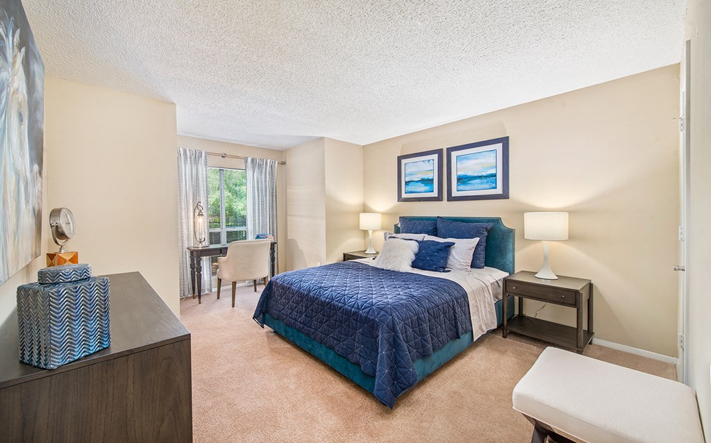 a bedroom with a bed and a desk and a window