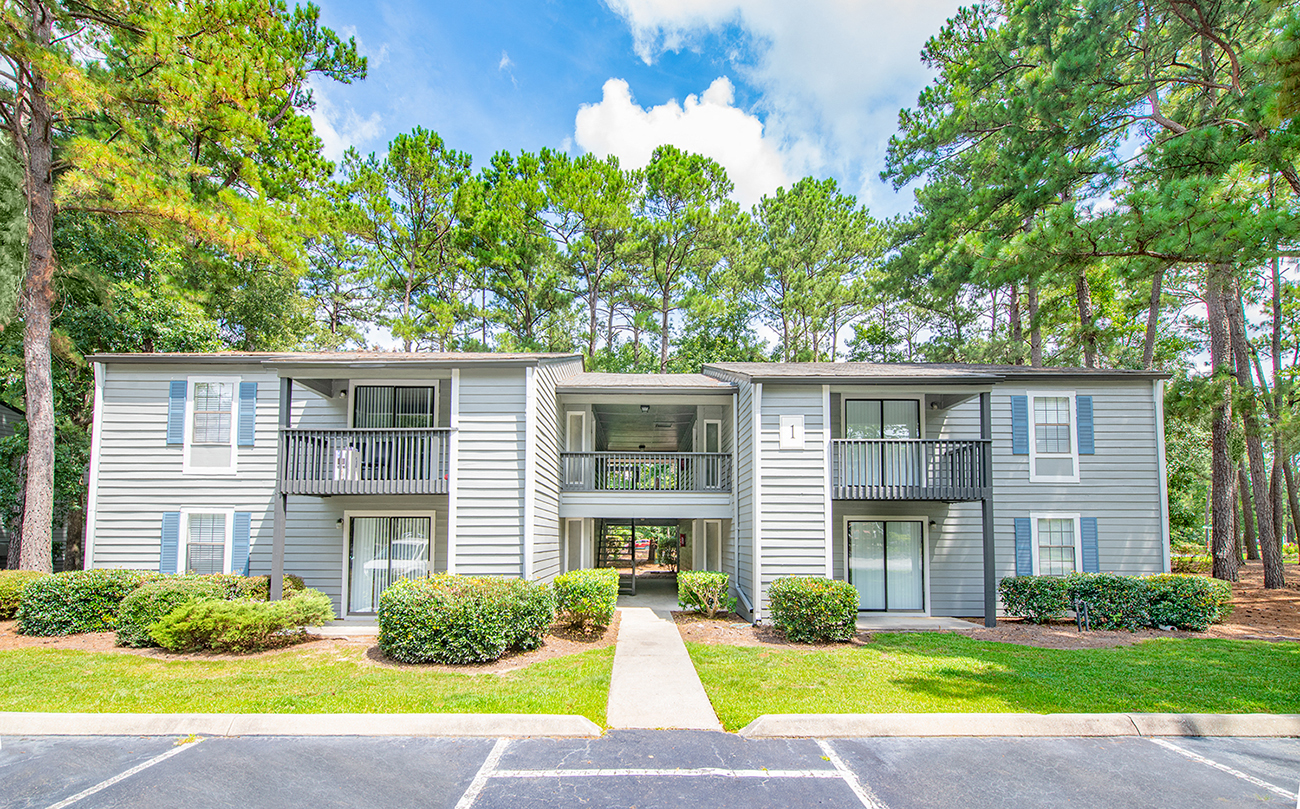 an apartment building with a lawn and trees