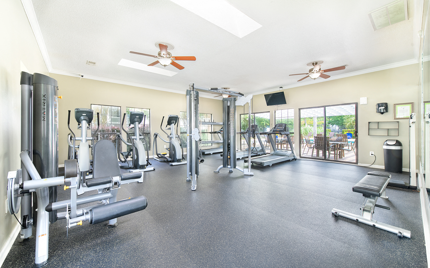 the gym has plenty of cardio equipment and glass doors to the patio