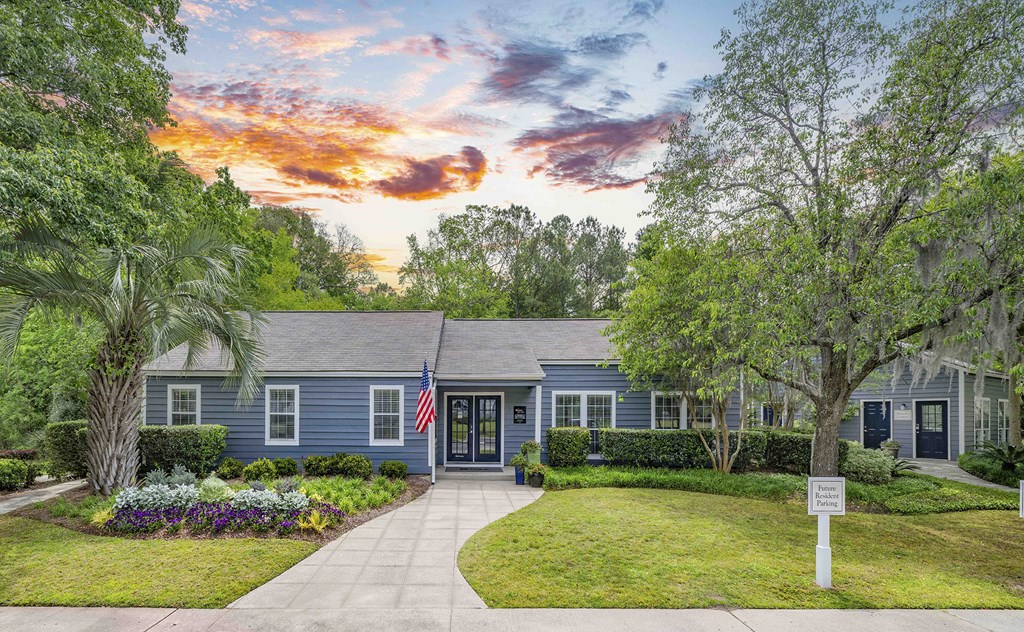 the front of a blue house with a lawn and trees