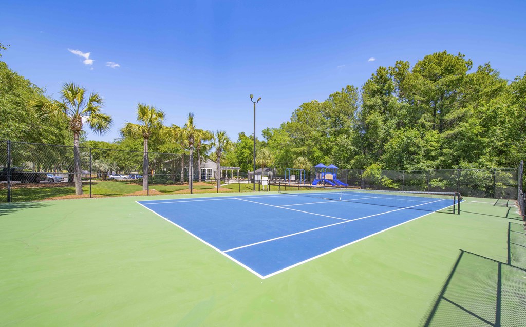 a tennis court with blue and green courts and trees