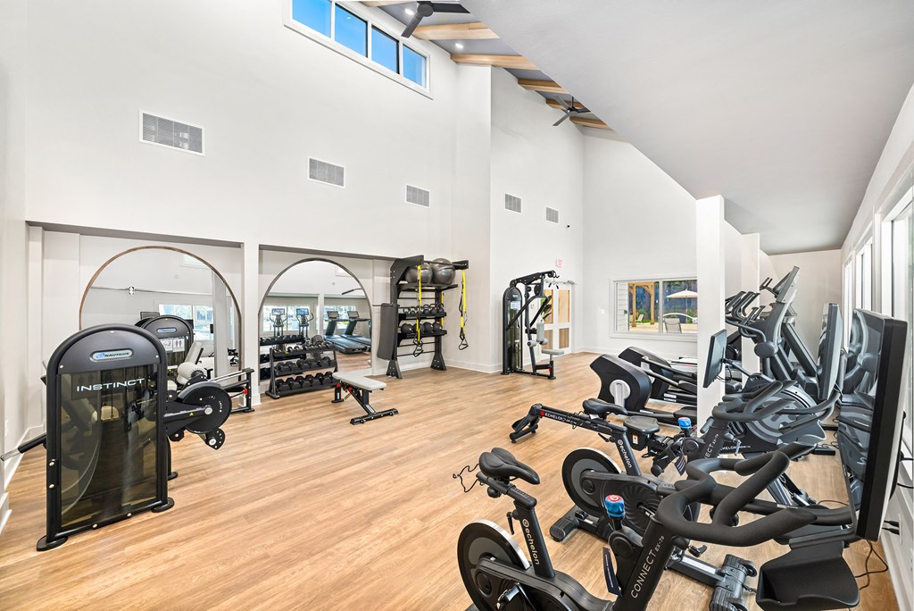 A gym with a variety of exercise equipment including treadmills, stationary bikes, and weight machines.
