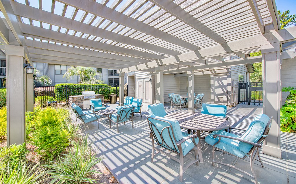a patio with blue chairs and tables and a white pergola