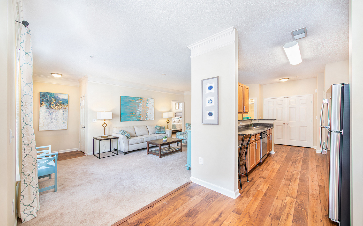a living room and kitchen with a refrigerator and a sink