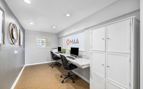 A white office space with a desk, chairs, and cabinets.