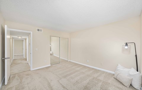 A spacious room with a carpeted floor and a doorway leading to another room.