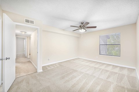 A room with a carpeted floor and a ceiling fan.