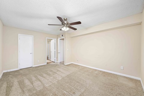 A room with a ceiling fan and carpeted floor.