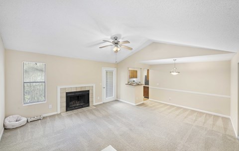 A spacious living room with a fireplace and a ceiling fan.