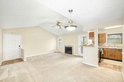 A spacious living room with a fireplace and a ceiling fan.