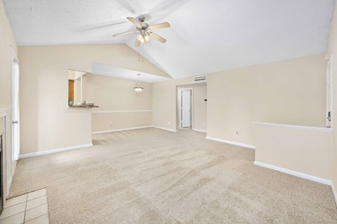 A spacious room with a ceiling fan and carpeted floor.