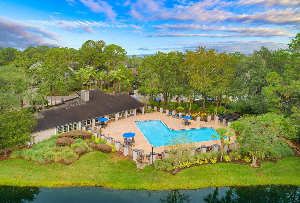 an aerial view of a swimming pool and a resort with a building and trees