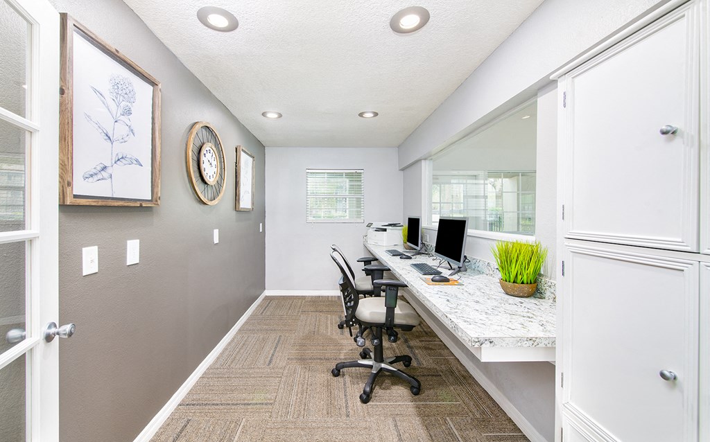 a home office with a long desk and chairs and a window