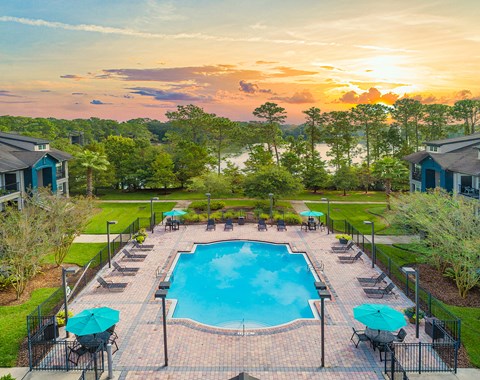 an aerial view of a swimming pool with umbrellas at sunset