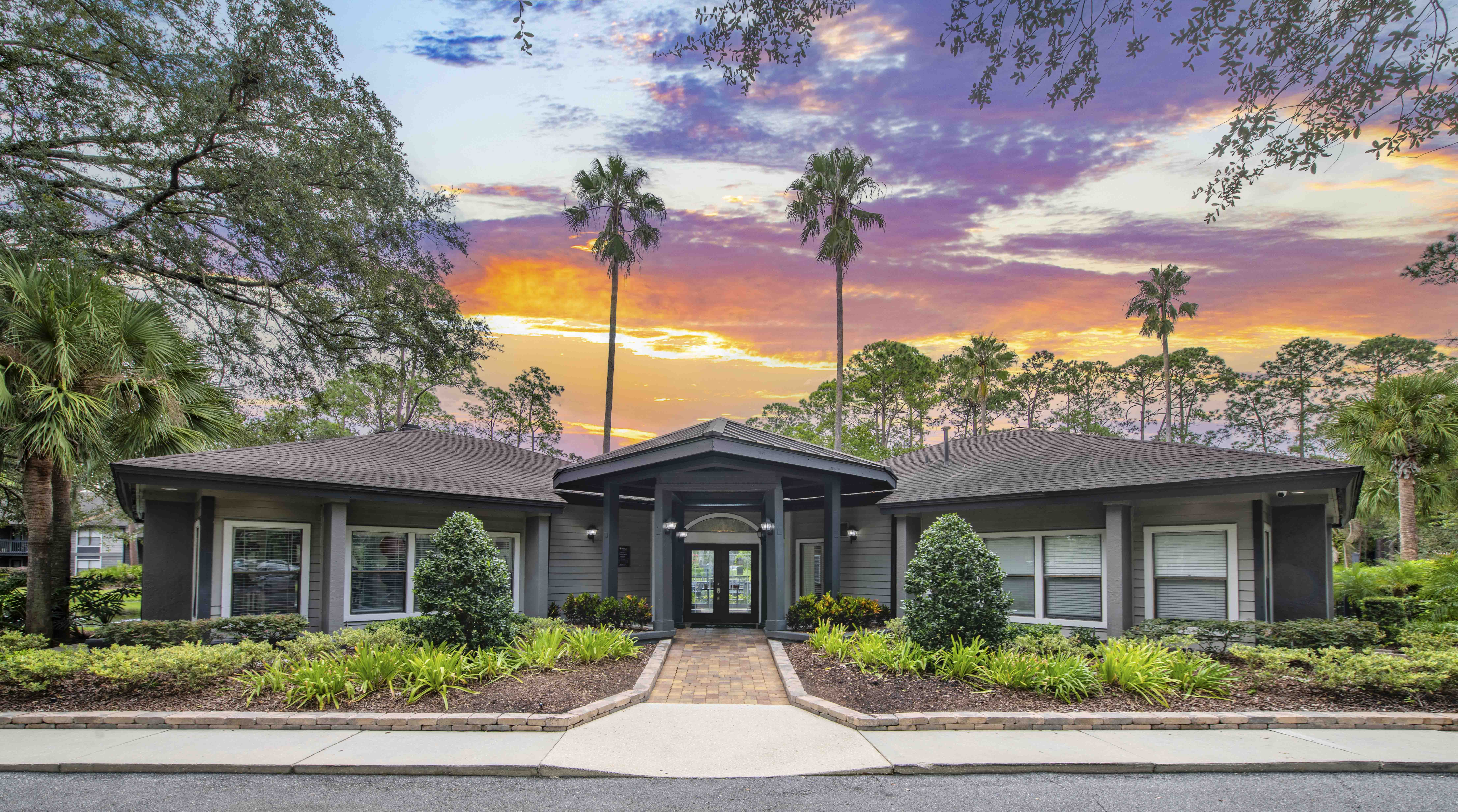 the front of a house with palm trees and a sunset