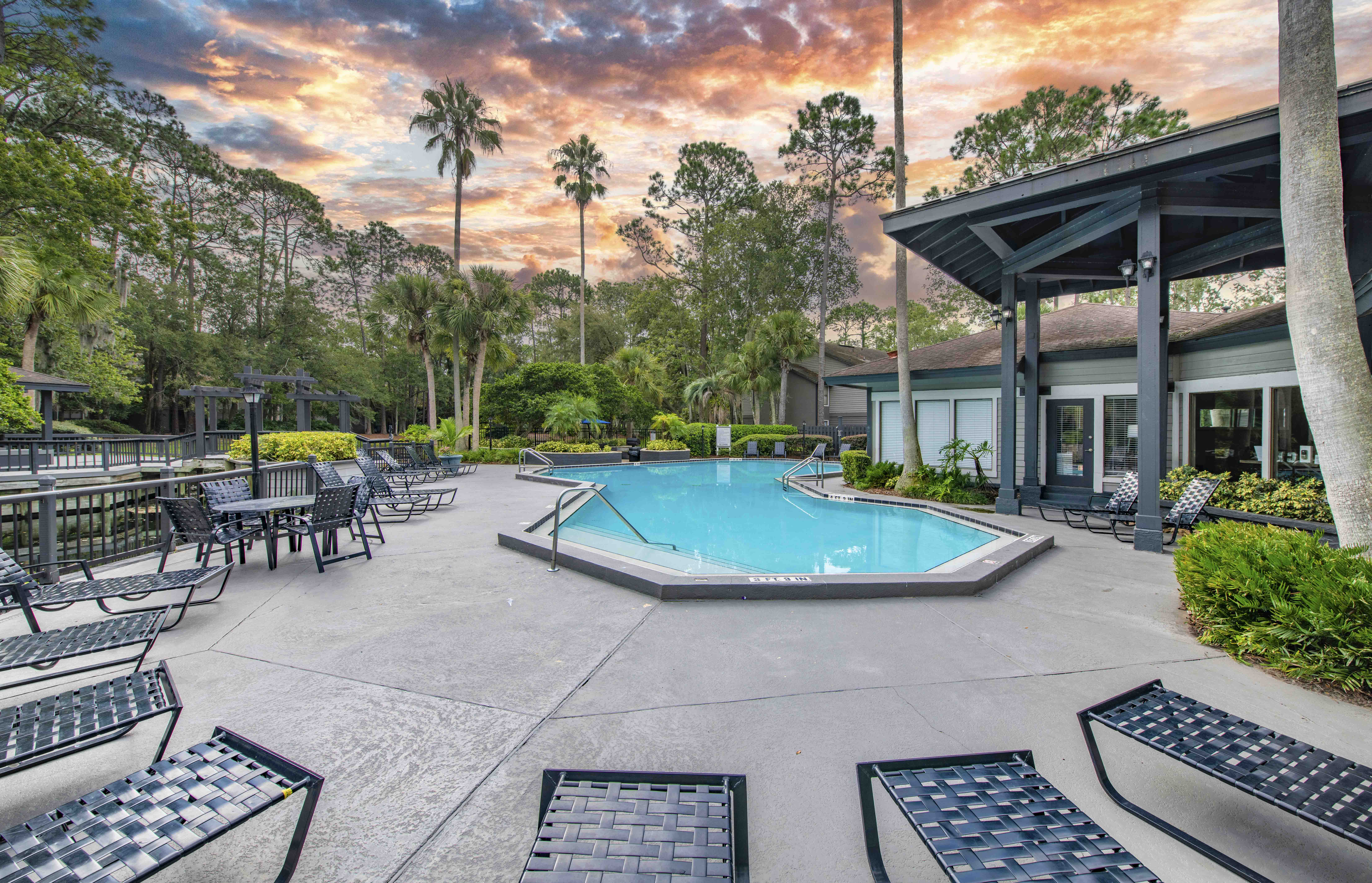 a pool with lounge chairs and a building with a resort style pool