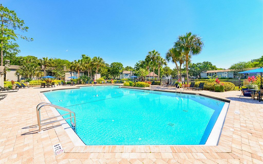 a swimming pool with palm trees and buildings in the background