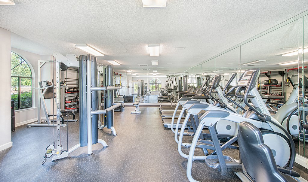 a gym with cardio equipment and weights on the floor