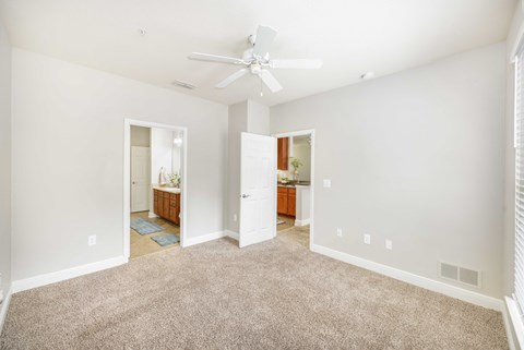 a spacious living room with carpet and a ceiling fan
