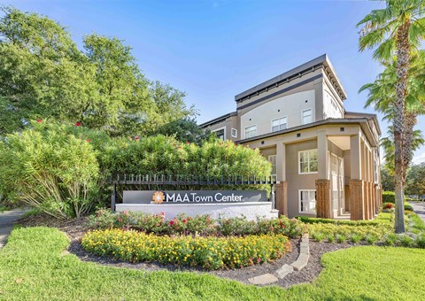 the front of the mia town center building with a sign and trees and plants