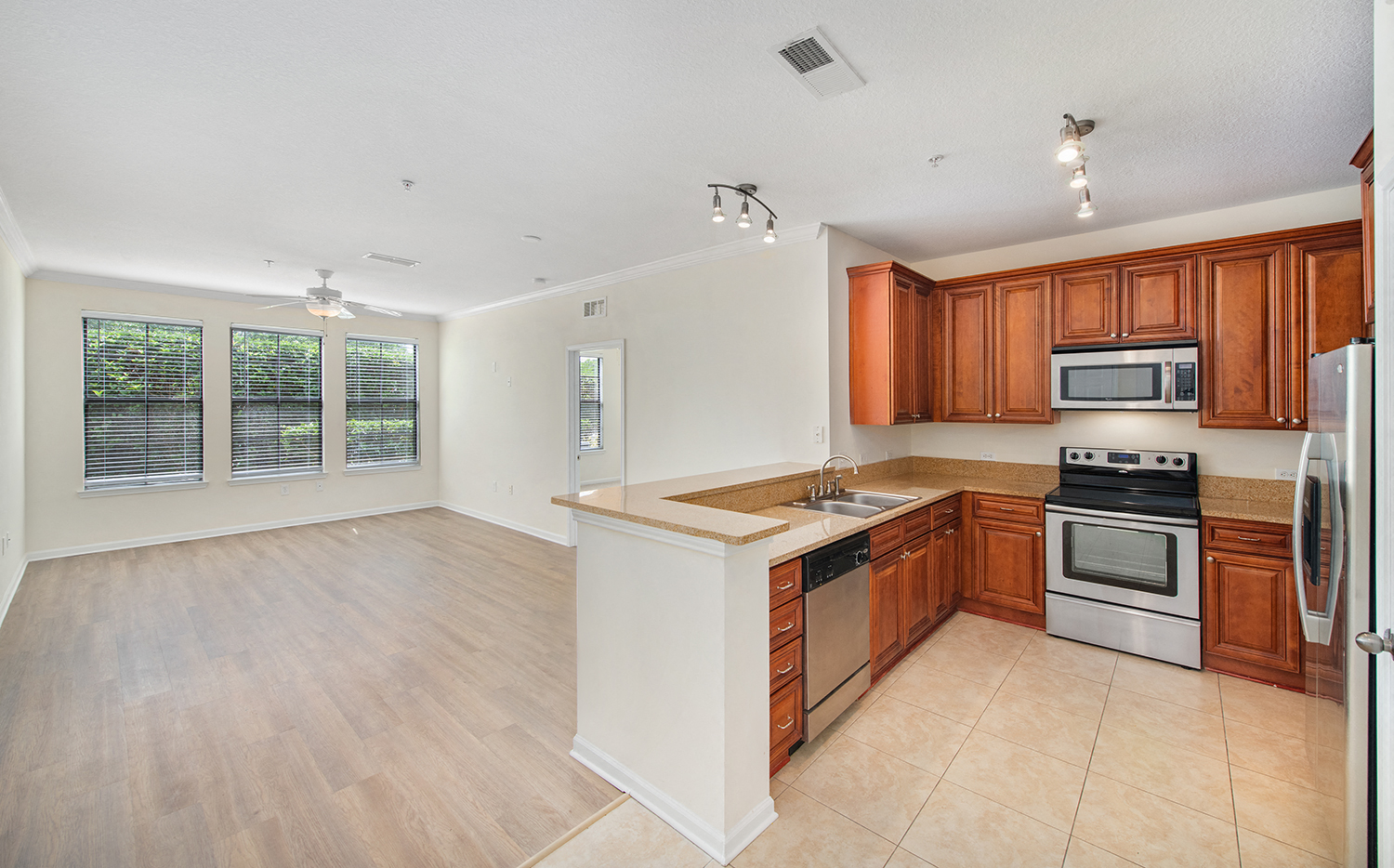 an empty kitchen with wooden cabinets and stainless steel appliances