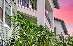 a swimming pool with chairs and palm trees in front of an apartment building