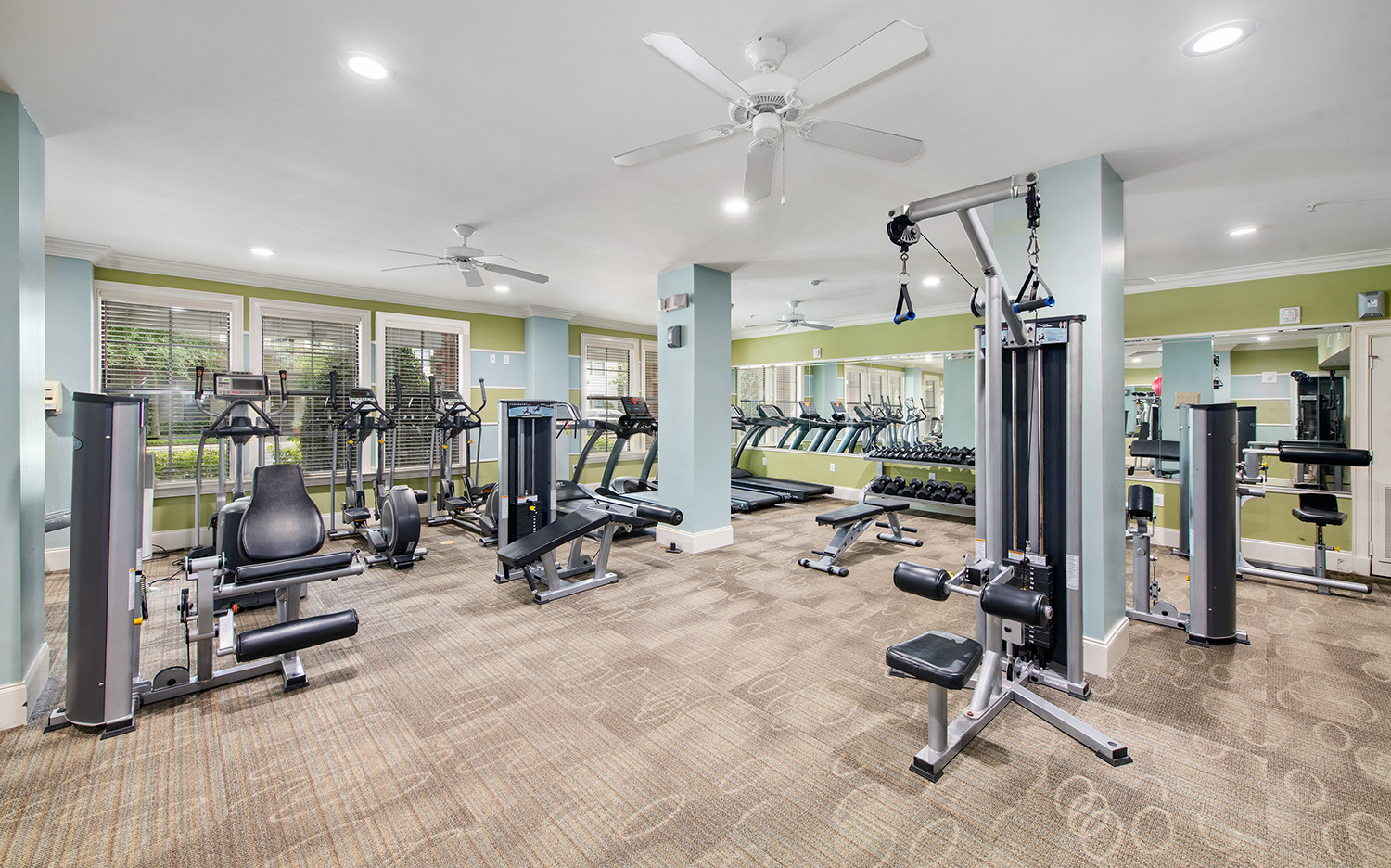 a gym with cardio equipment and weights in a building with green walls