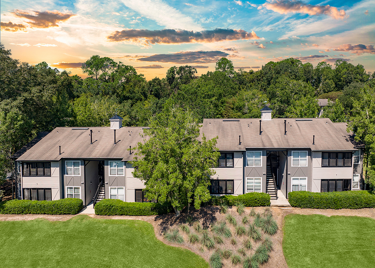 an aerial view of an apartment building with green lawns and trees
