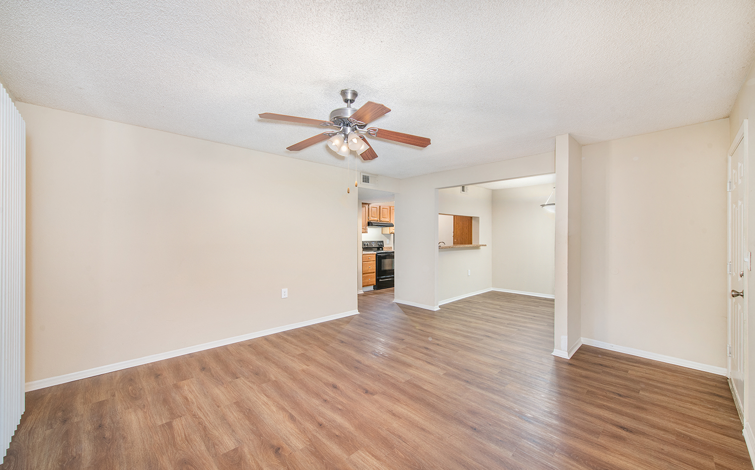 an empty living room with wood flooring and a ceiling fan