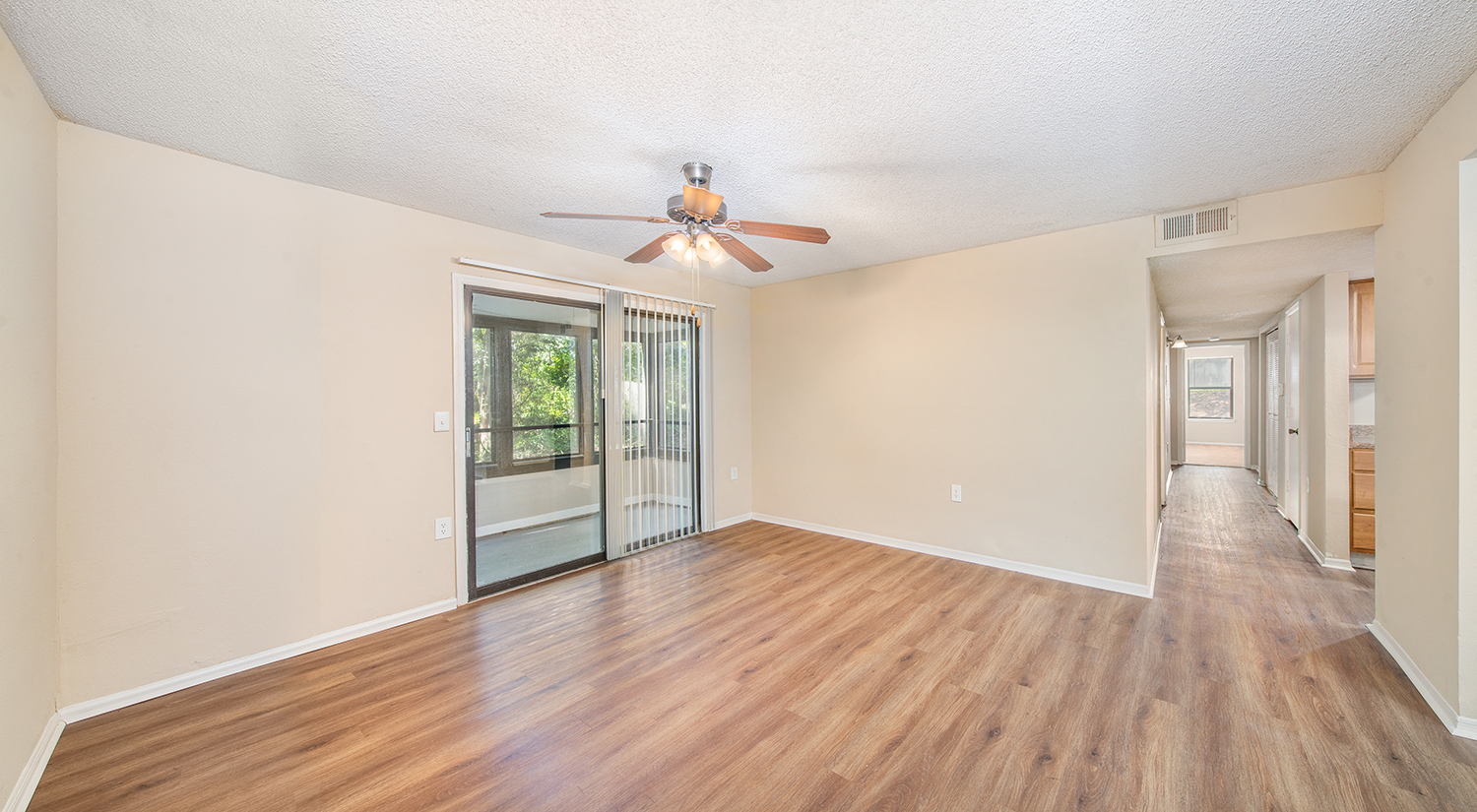 an empty living room with a ceiling fan and a sliding glass door