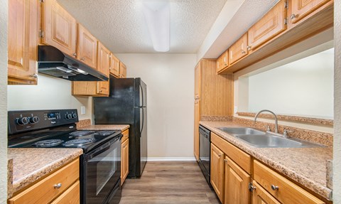 a kitchen with wood cabinets and black appliances and a sink