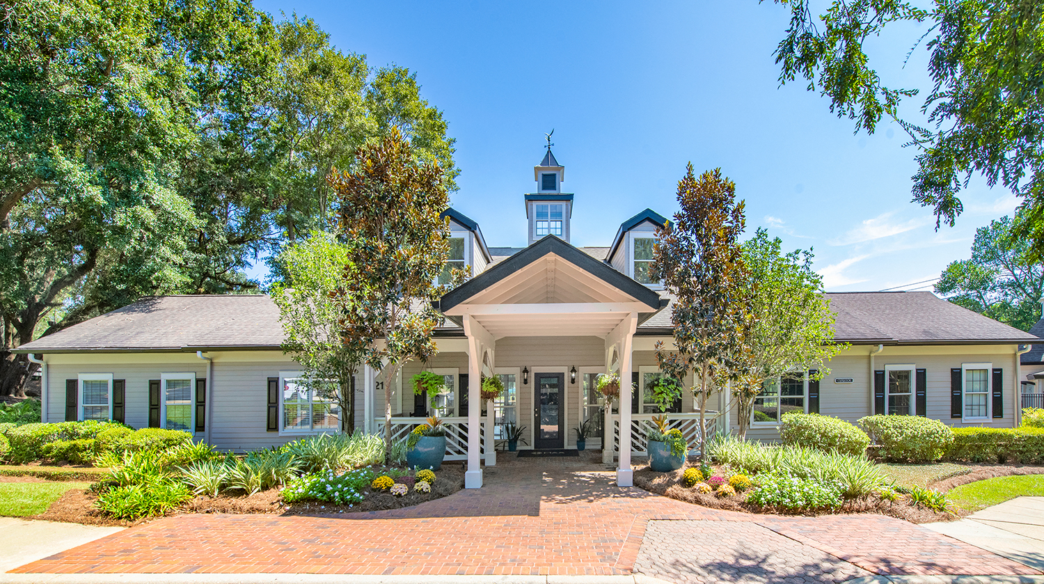 the front of a white house with a porch and trees