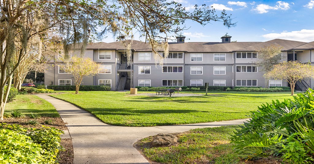 A residential building with a well-maintained lawn and trees.