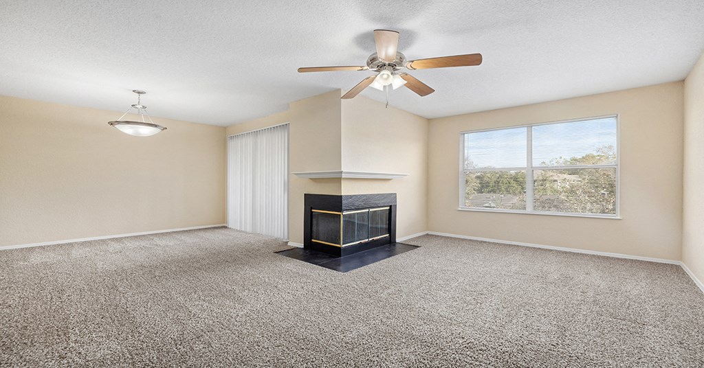 A living room with a fireplace and a ceiling fan.