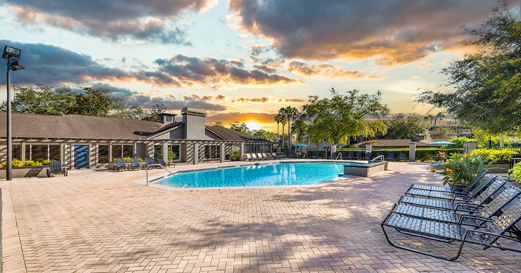 A large outdoor swimming pool surrounded by a patio and lounge chairs.