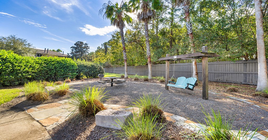 A backyard with a bench, a table, and a fire pit.