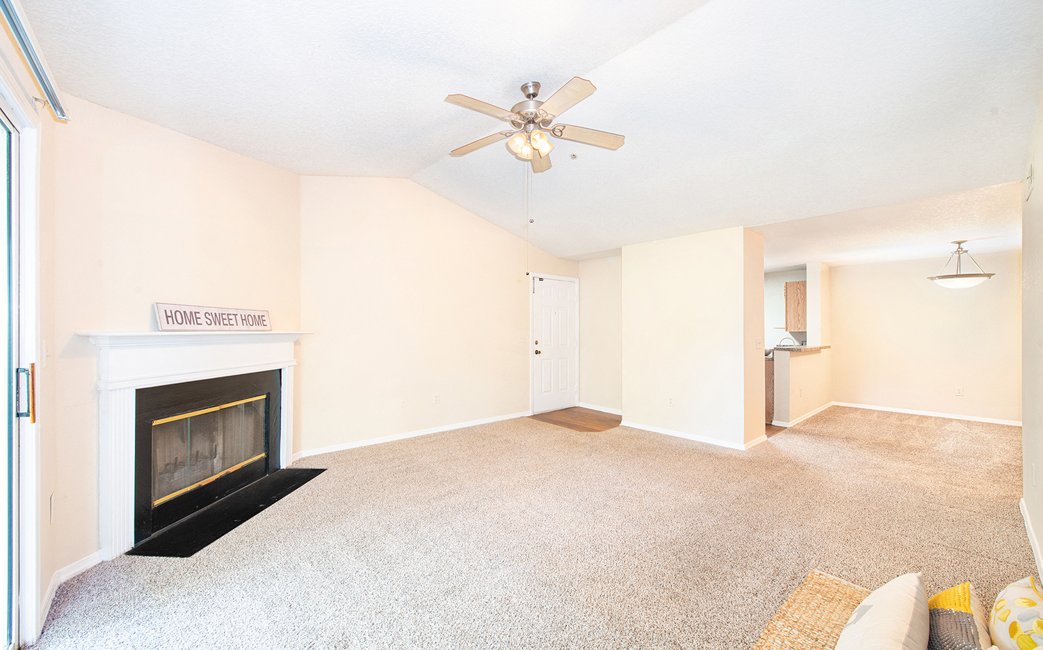 an empty living room with a fireplace and a ceiling fan