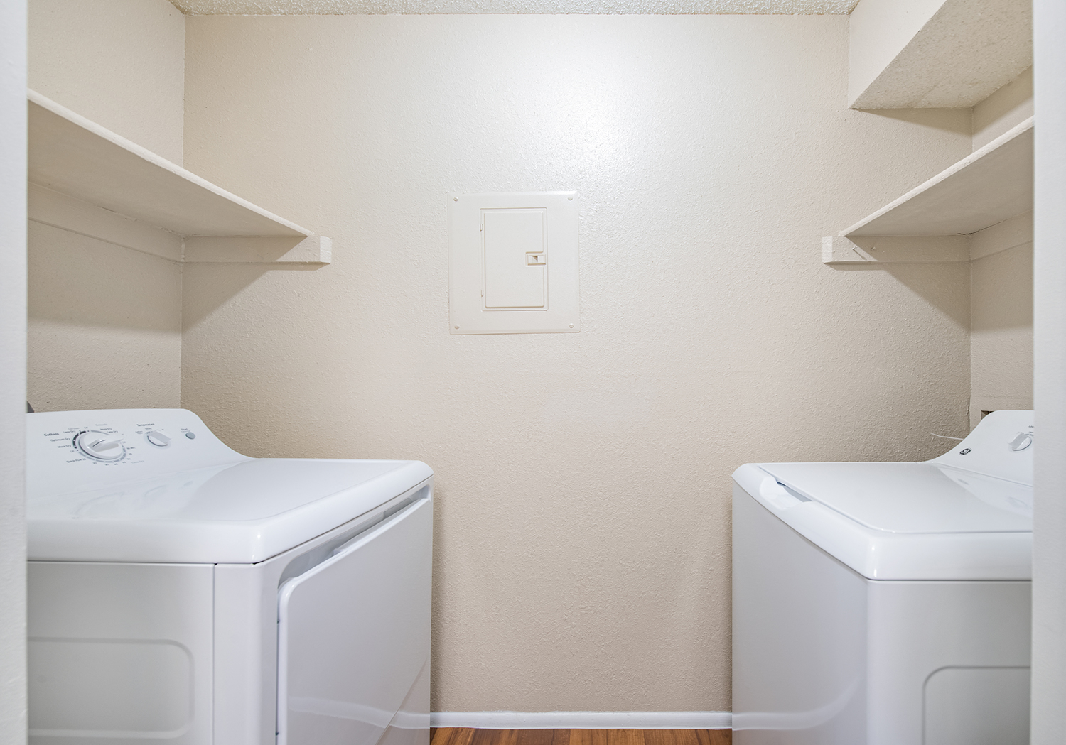 an empty laundry room with two washers and a dryer