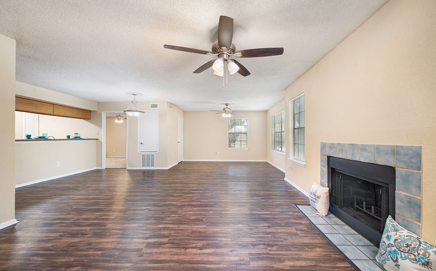 an empty living room with a fireplace and a ceiling fan