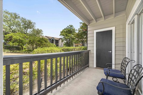 a balcony with two chairs and a door to a house