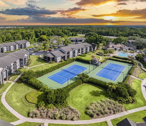 a property with multiple tennis courts and buildings at sunset