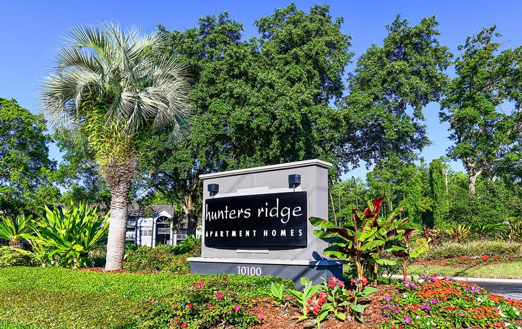 a sign for hunters ridge apartments in front of trees
