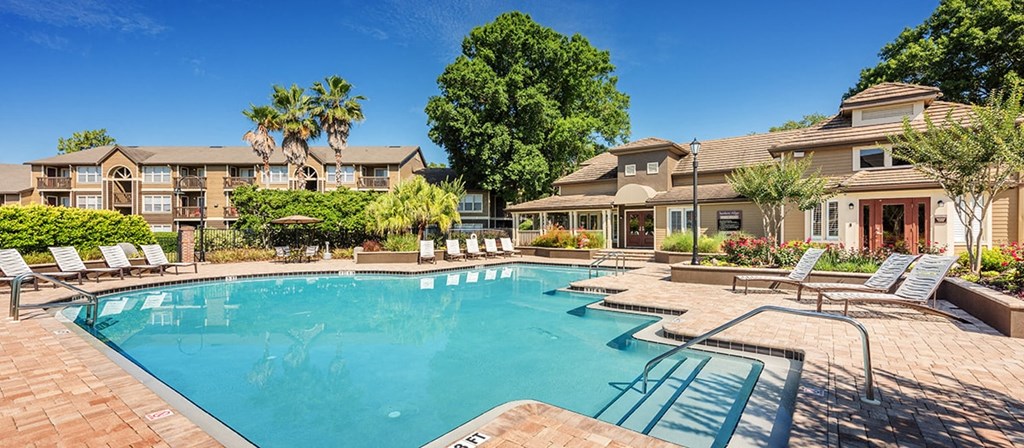 a swimming pool with chairs and a building in the background