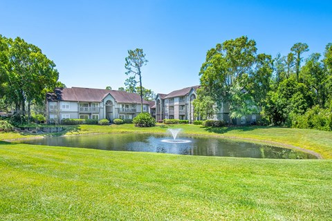 a large pond with a fountain in front of some apartments