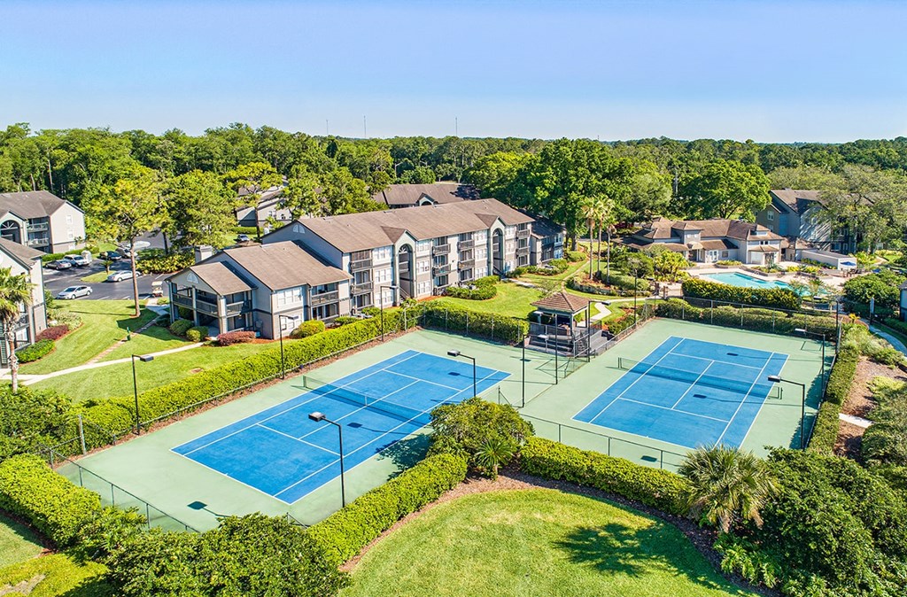 an aerial view of two tennis courts with buildings in the background