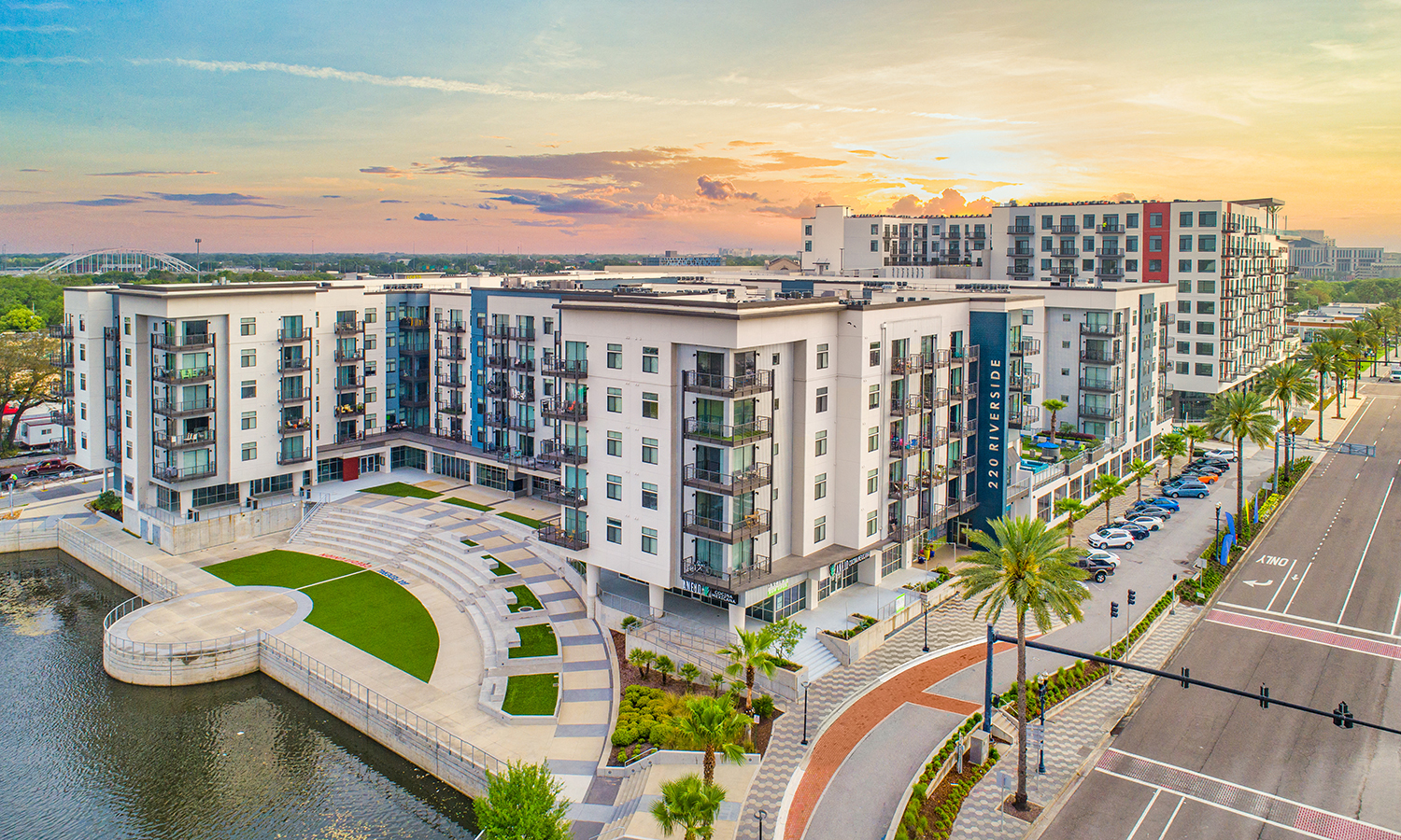 an aerial view of an apartment complex with a sunset over the water