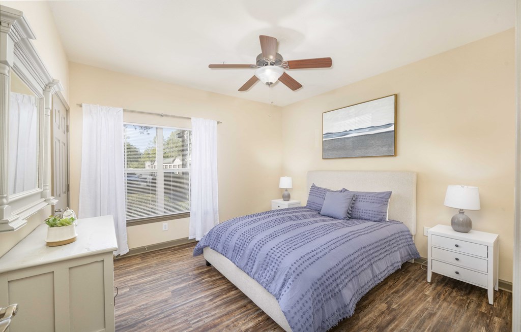 A bedroom with a bed, nightstand, and window.