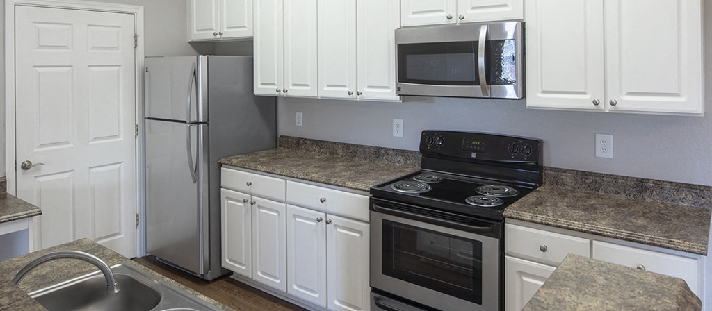 a kitchen with white cabinets and stainless steel appliances and granite counter tops