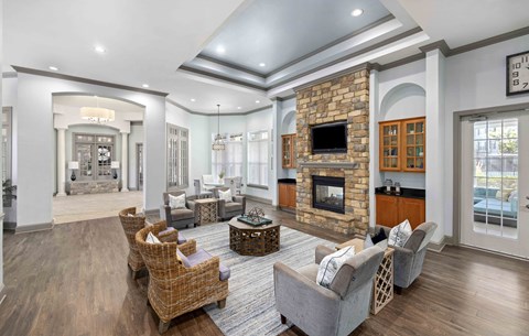 A living room with a stone fireplace and a large mirror on the wall.