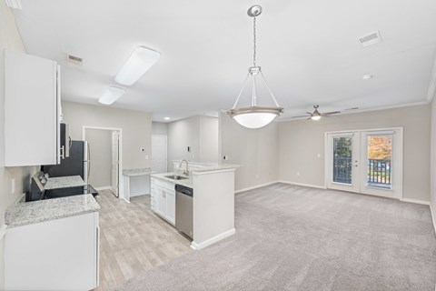A spacious kitchen with white cabinets and a grey countertop.